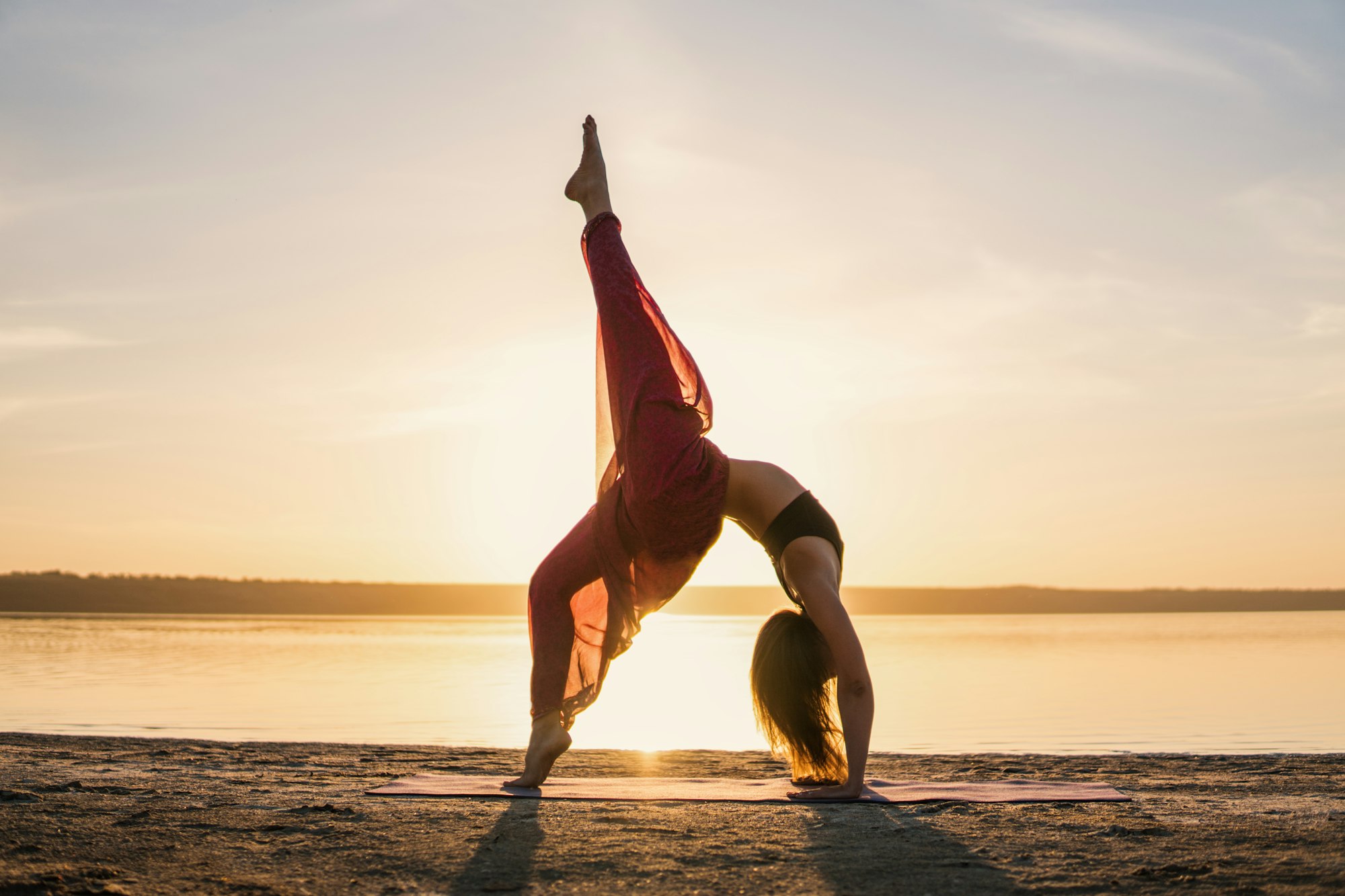 Silhouette yoga woman on the beach at sunset