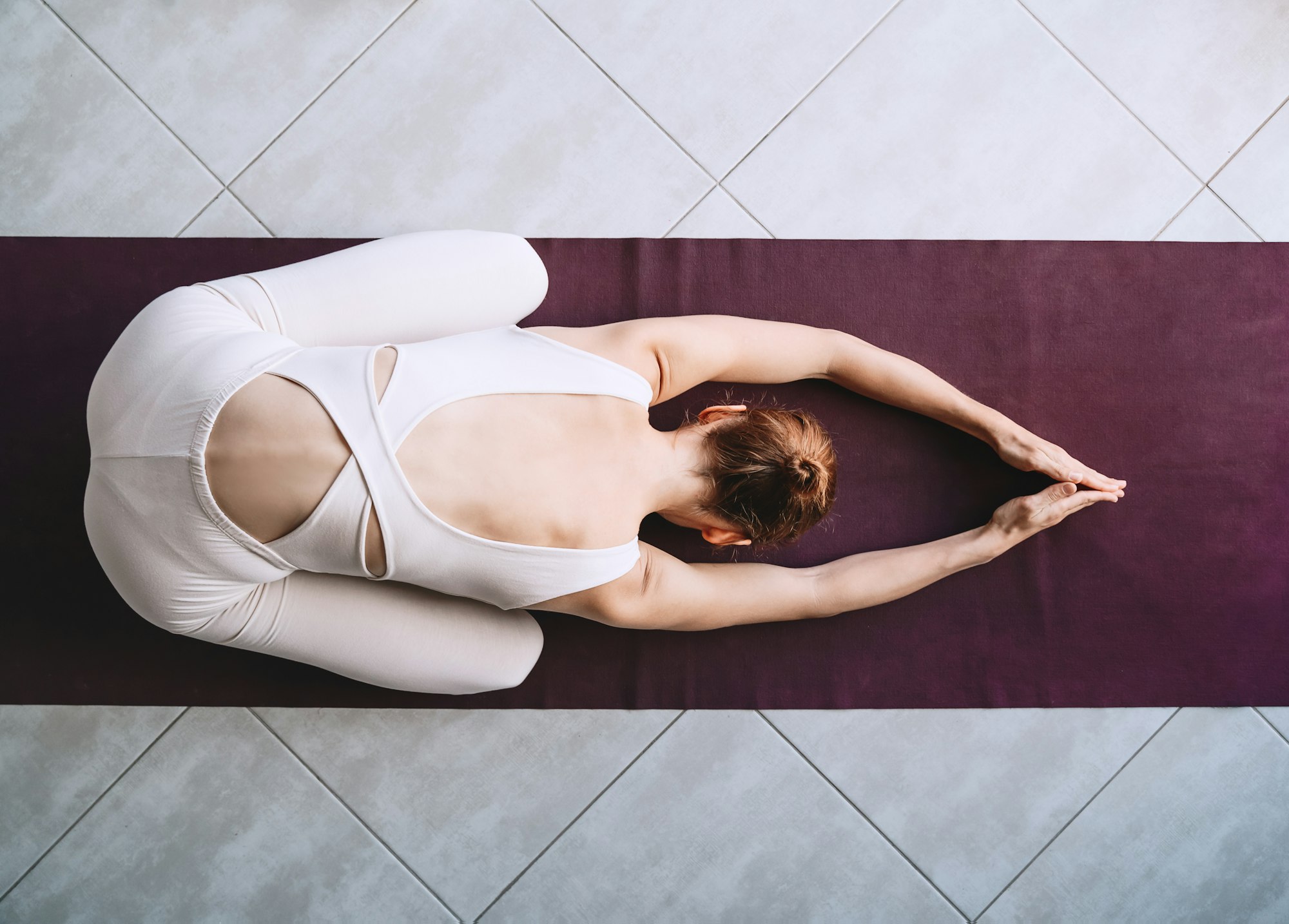 Young woman practicing yoga on yoga mat indoors.